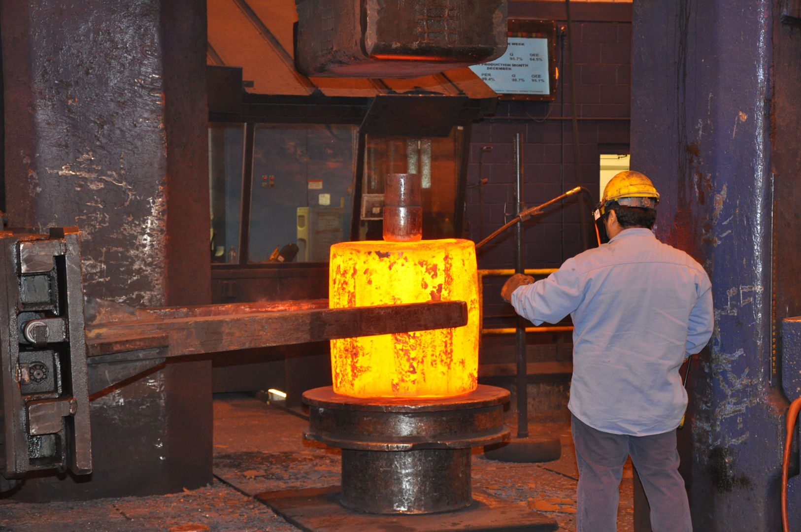 Ring preform with a worker punching a hole in the middle to create a hollow