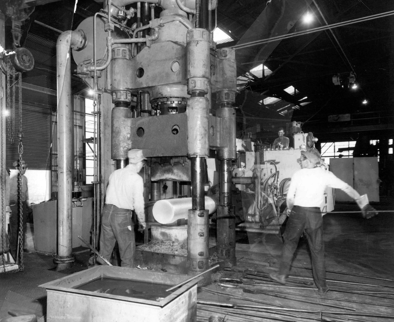 EArly days at Scot Forge, workers operating a large forging press inside a factory. Scot Forge