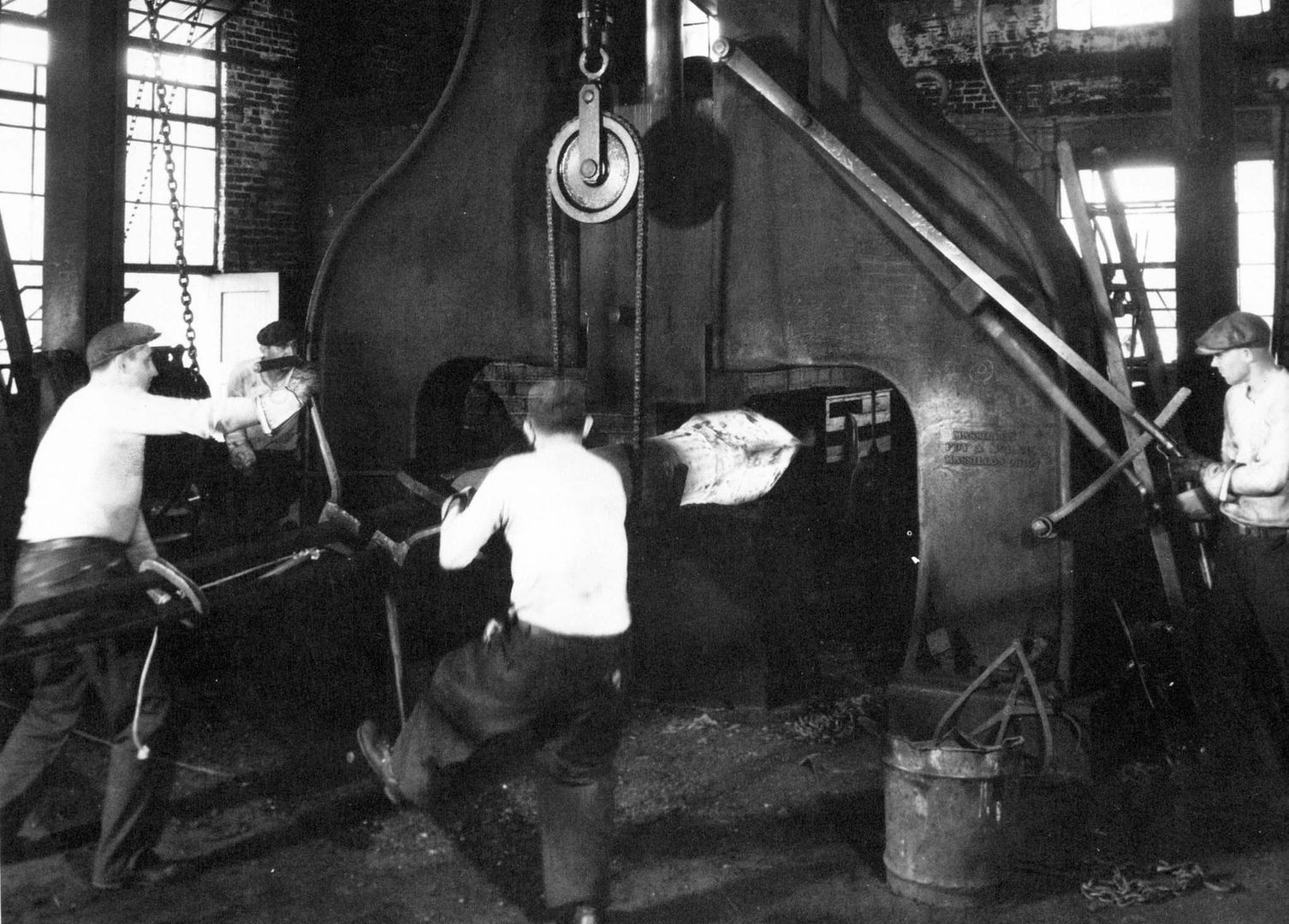 Workers operating machinery at Scot Forge, preparing forged metal Our History